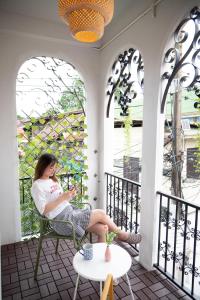 a woman sitting in a chair on a porch at Bangkok Neighborhouse - Guesthouse in Bangkok