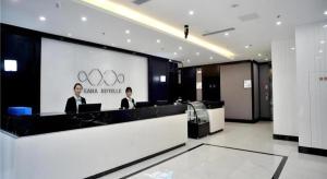 deux personnes sont assises à un comptoir dans un bureau dans l'établissement Xana Hotelle Rizhao Lanshan District Government, à Lanshantou