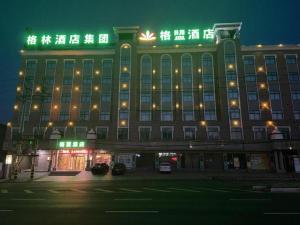 un grand bâtiment avec des lumières vertes au-dessus dans l'établissement GreenTree Alliance Hotel Tongcheng Tong'an Road Beidao, à Wangguolu