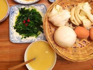 une table recouverte de paniers de nourriture avec des œufs et des légumes dans l'établissement GreenTree Alliance Hotel Tongcheng Tong'an Road Beidao, à Wangguolu