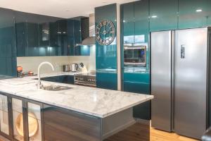 a kitchen with blue cabinets and a refrigerator at Honeysuckle Executive Apartments in Newcastle