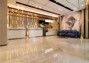 長沙市にあるEcharm Hotel Changsha Wuyi Square Railway Metro Stationの青いソファと目が描かれた壁のあるロビー