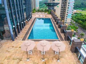 恵州市にあるHaoyikang Hotelのパラソルのある建物のプールの上空からの眺め