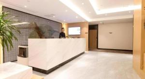 un homme debout derrière un comptoir dans un hall dans l'établissement Green Tree Inn Nanchang Zhongshan Road Bayiguan, à Nanchang