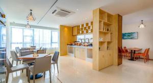 une salle à manger avec tables et chaises et une cuisine dans l'établissement City Comfort Inn Zhanjiang Central People's Hospital High-speed Railway Station, à Tchia-k'am
