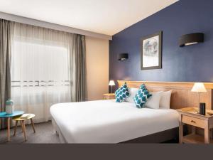 a hotel room with a large white bed and a window at Aparthotel Adagio La Défense Esplanade in Puteaux