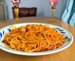 a plate of spaghetti on a table with two wine glasses at ジーアール柳井 in Yanai