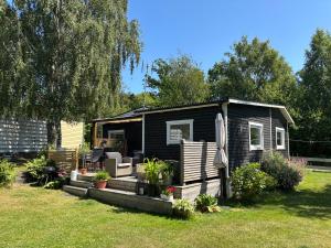a black tiny house in a yard at Cozy cottage by the sea, near Kullaberg in Farhult