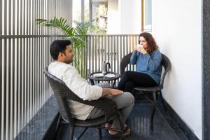 un hombre y una mujer sentados en sillas en un balcón en FabHotel La Paz Stay B&B, en Nueva Delhi