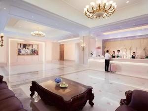 a man standing in a large room with a table at Vienna Hotel Zhengzhou East High-Speed Railway Station in Zhengzhou