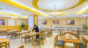 a woman sitting at a table in a restaurant at Vienna Hotel Hubei Xiangyang Tang City Gulou in Xiangyang