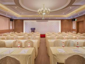 une salle de banquet avec des tables et des chaises blanches et un lustre dans l'établissement Vienna Hotel Shanghai Hongqiao National Exhibition Center Fengxi Beiqing Road, à Fengxi