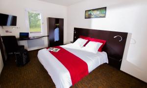Cette chambre comprend un grand lit avec des oreillers rouges. dans l'établissement Hôtel Akena De Clermont-Creil, à Agnetz