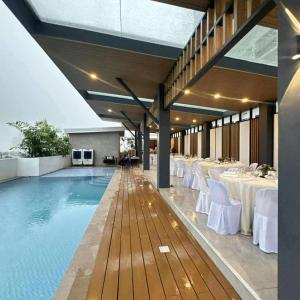 JTower Residences beside SM Jmall Mandaue في مانداوي سيتي: مسبح بالطاولات البيضاء والكراسي البيضاء