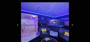 a room with purple lighting and a chair and a tub at La Gold Room jacuzzi et sauna in Perpignan