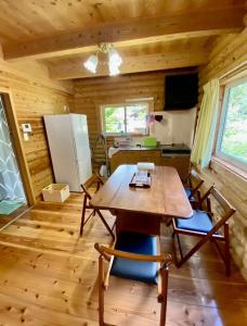 a dining room with a table and chairs and a refrigerator at コテージ杏庵 Cottage Anzuan in Minamioguni