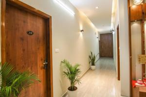 a hallway with potted plants and a wooden door at FabHotel K9 Regency in Dorāha