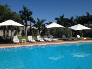 a group of chairs and umbrellas next to a pool at Condado Hotel Casino Santo Tome in Santo Tomé