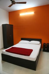 a bed in a room with an orange wall at Go COOL-IN in Yercaud