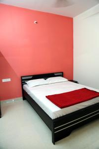 a bed in a room with a red wall at Go COOL-IN in Yercaud