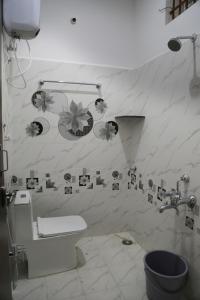 a bathroom with a toilet and flowers on the wall at Go COOL-IN in Yercaud +8 photos