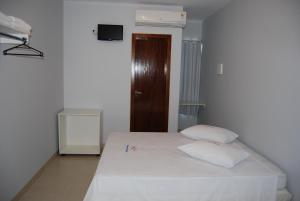 ein Schlafzimmer mit einem weißen Bett mit zwei weißen Kissen in der Unterkunft Pousada Santana - Trindade Goiás in Trindade