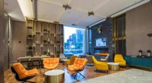 a lobby with orange and yellow chairs and a large window at Echarm Plus Hotel Wuhan Wenhua Boulevard Dahualing Subway Statiom in Wuhan