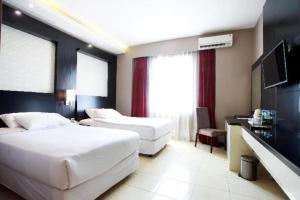 a bedroom with two beds and a flat screen tv at Karlita Hotel Tegal in Tegal