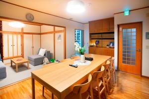een keuken en een woonkamer met een grote houten tafel bij KazeVillaFurano in Furano