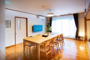 een eetkamer met een houten tafel en stoelen bij KazeVillaFurano in Furano