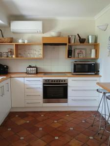 a kitchen with white cabinets and a stove top oven at Dennis Cottage Clare Valley , Auburn in Auburn