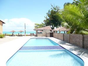 a swimming pool in a villa with the ocean in the background at Privê Village Maragogi in Maragogi