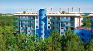 a blue and white apartment building with trees at Klim Hotel in Buriram