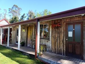 a wooden house with a porch and a door at Greenstone Retreat in Kumara