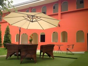 une table avec un parasol devant un bâtiment dans l'établissement Thada Chateau Hotel, à Ban Bu Lamduan