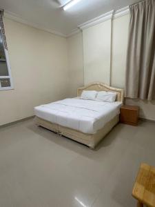 ein Schlafzimmer mit einem weißen Bett in einem Zimmer in der Unterkunft الحى التجارى RED-13 ALhaddad in Salalah