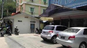 two cars parked in a parking lot in front of a building at H3 Hotel in Tanjung Balai Karimun