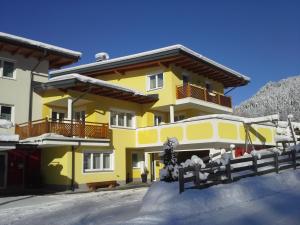 una casa amarilla con una cerca en la nieve en Ferienhaus Kerstin, en Wagrain