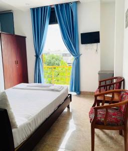 a bedroom with a bed and a chair and a window at Cát Tường Homestay in Danang