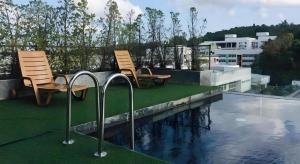 two chairs sitting next to a swimming pool on a roof at Neca Reiche in Hat Yai