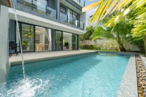 an infinity pool with a waterfall in front of a house at Luxury 5BR Pool Villa near Beach and Golf - Laguna Park 2 in Ban Phru Champa