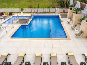 - une vue sur la piscine entourée de chaises dans l'établissement ibis Styles Barcelona Sant Joan Despi, à Sant Joan Despí