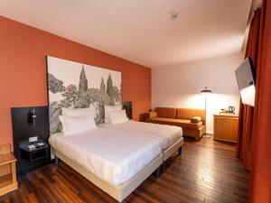 une chambre d'hôtel avec un grand lit et un canapé dans l'établissement Hotel Mercure Roma Corso Trieste, à Rome