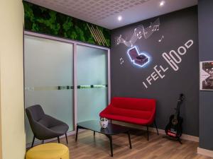 a waiting room with a red chair and a guitar at Ibis Győr in Győr +75 photos
