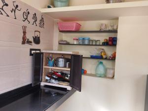 a kitchen with a shelf with food and utensils at The Homely Stay - Chandransh Homestay in Udupi