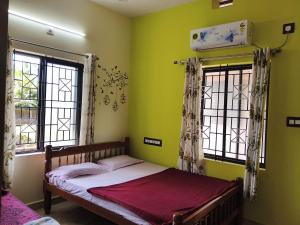 a bedroom with a bed with green walls and windows at The Homely Stay - Chandransh Homestay in Udupi