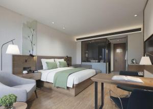 a bedroom with a large bed and a desk and a chair at Vatica Hengshui Halixun Peace Hospital Hotel in Hengshui