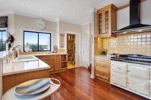 a large kitchen with wooden cabinets and a table at Luxury Mansion 7bdrm 6bth pool pizza ovn 25mns CBD in Silverdale