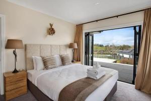 a bedroom with a large bed and a large window at Luxury Mansion 7bdrm 6bth pool pizza ovn 25mns CBD in Silverdale +30 photos