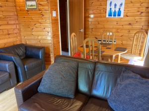 a living room with a leather couch and a table at Cosy log cabin in Snowdonia 357 in Trawsfynydd